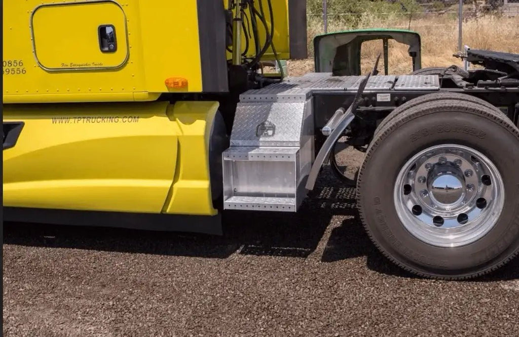 Aluminum step tool box mounted on a yellow semi truck beside the rear cab wheel