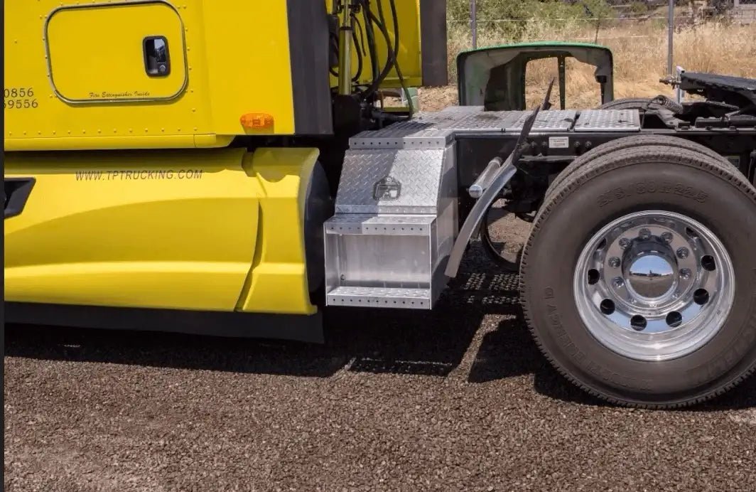 Aluminum step tool box mounted on a yellow semi truck beside the rear cab wheel