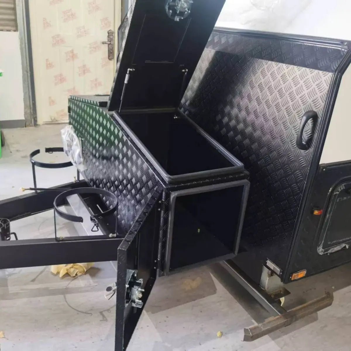 Black checker plate storage boxes installed on both sides of a trailer drawbar assembly