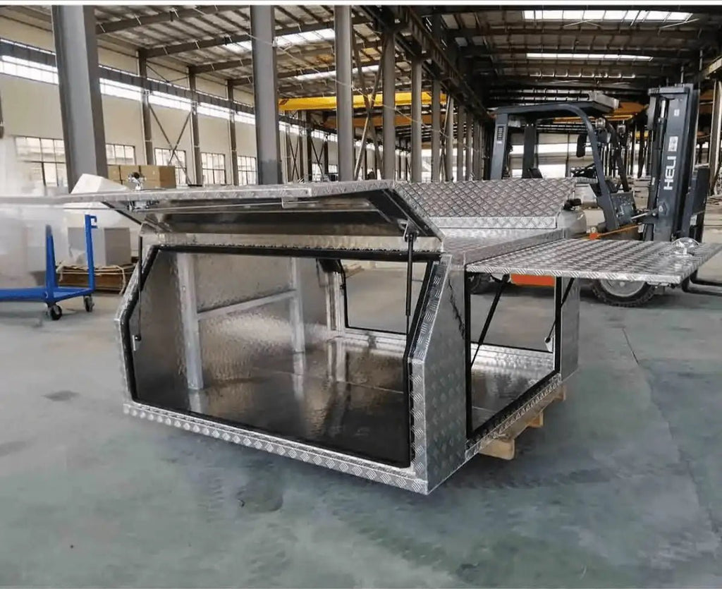 Factory view of checker plate aluminum canopy toolbox with gullwing lids and side door open